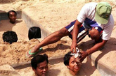 泰国武里南，一名男子为沙浴中的病人擦汗。沙浴疗法将人埋在沙子中直至脖颈处，被认为可以治疗多种病症，甚至是癌症和精神病。