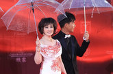 刘晓庆身穿高开叉礼服，手持红色晚礼服包。