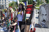 FEMEN组织的成员自制“人体弹弓”投射白俄罗斯总统卢卡申科的画像。