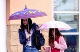 蕾切尔-比尔森带妹妹买玩具，翘肩外套加牛仔裤时尚靓丽，撑紫色雨伞可爱至极。