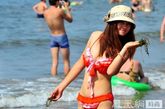 近日，全国各地引来高温“桑拿天”，人们纷纷来到海边、泳池避暑。图为青岛游客在海边玩耍，享受清凉。