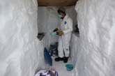 在这张2011年7月15日的照片中，在一条从厚达2英里的格陵兰岛冰原中挖出的深沟中，乔治亚理工大学的研究员布兰登·斯特里利斯正在保存“峰顶站”（研究站位于广大冰原的中心）的冰样。横跨格陵兰岛白色地域，由世界各地的研究者组成的小团队正在搜寻关于全球变暖对格陵兰岛的冰构成潜在影响的线索。
