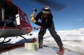 连接于一架待命的直升机上的绳索，来自纽约大学的北极研究员卡尔·格拉丁斯为固定GPS地震检波器（又叫做“地理鹅卵石”），将钢桩打入冰下。这台仪器设计用于跟踪冰川（位于格陵兰岛冰原的边缘，格陵兰岛伊卢利萨特外的雅各布布港冰川顶部，）移动。主研究员，纽约大学的大卫·霍兰希望最终能布置数十个这样的装置以帮助测量格陵兰岛的冰损失量。