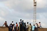 8月17日，在塞内加尔首都达喀尔，球迷们爬上一个足球场的围墙观看比赛。新华社记者 刘宇摄