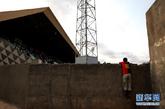 8月17日，在塞内加尔首都达喀尔市中心，一个身穿阿根廷球星梅西10号球衣的小球迷趴在足球场围墙上观看比赛。新华社记者 刘宇摄