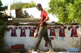 8月24日，在塞内加尔首都达喀尔郊区，一个男孩从画着球衣的房前走过。新华社记者 刘宇摄