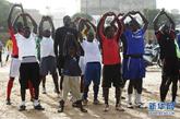 8月23日，在塞内加尔首都达喀尔郊区，一个小球迷和专业球员一道进行身体训练。新华社记者 刘宇摄