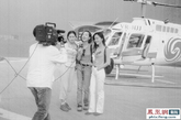 1997年6月香港回归前夕，刚刚一岁的凤凰卫视还是一只小麻雀，她很希望真正飞上天空看一看自己诞生的地方。这时，另一只小鸟——一家新成立的直升机公司找上门，为了创牌子，他们愿意免费让凤凰卫视航拍香港，于是两只小鸟一齐飞上蓝天，尝到了变凤凰的感觉。图为鲁豫在喷绘着凤凰标志的直升机前，摆Pose。【感谢凤凰卫视北京公关部供稿】