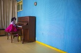 一个女孩在平壤长旺小学的教室内弹钢琴。