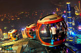 游客在摩天轮的球舱内观赏广州夜景，画面右部为广州的新中轴线。