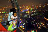 一名女孩在摩天轮的球舱内凝视城市璀璨的夜景。