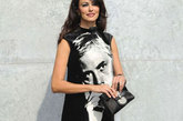  玛莉亚·嘉西亚·古欣娜塔（Maria Grazia Cucinotta在2012春夏米兰时装周上身着Emporio Armani黑色裙亮相，大大的头像印在群身上十分惹眼。
