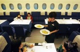 2009年1月22日，在A380飞机的“机舱”中，打扮成空姐的一名女服务员在为顾客提供服务。台北的一家餐厅的名字命名为巨型空中客机，一位台北的企业家自2008年11月开始经营这种服务。经过包装的，餐厅有同航行的客机几乎一样的外观和功能，销售全套高端西餐，有时还用塑料托盘。