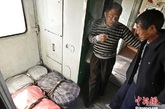 图为两位沿线村落的农民正在车厢连接处抽烟聊天，他们俩常常搭乘6417前往北京卖水果，这几个小竹篮就是他们的。 中新社发 张浩 摄
