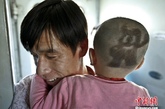 图为一对火车上的父子，孩子的头发剃成了上海世博会吉祥物海宝的图案。中新社发 张浩 摄