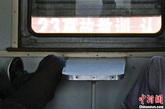 图为两位旅客正在悠闲地睡觉，火车路过顺义站，窗外是“牢记7.23事故教训”的横幅。6417几乎没出过事故，但最近车组人员也开始提高了警惕。中新社发 张浩 摄