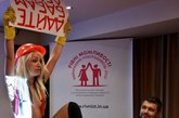 在一个为促进乌克兰男女平等就业的会议上，一位来自乌克兰“FEMEN”女性组织的金发美女杀入会场，一如往常的“轻装”上阵，手持标语，为女性争取劳动报酬。