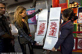 2011年10月15日，北京，外国游客在胡同节上选购中国剪纸。