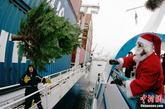 2011年12月8日，德国汉萨市港口，一名着圣诞老人装的工作人员将圣诞树抛向轮船。

