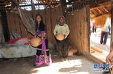 水平村村民阿炳（右）和女儿（左）在低矮的茅草屋里整理东西准备搬进新家。