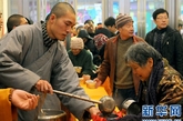 一位少林寺僧人在给市民盛装“少林五行腊八粥”（图片来源：新华网  摄影：王颂）
