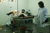 该产妇已经顺利产下了一名男婴，这是她躺在手术台上，等待医生给她把分娩时缝合因产道狭窄婴儿头无法通过产道而切开的阴道。 