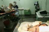 这是她分娩的孩子，小家伙睡得真香啊，他的母亲在一名医生帮助下缝合被切开的产道。