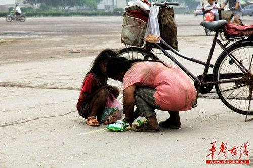 一名中年妇女和一名小女孩正在捡拾散落在地的方便面. 网友供图