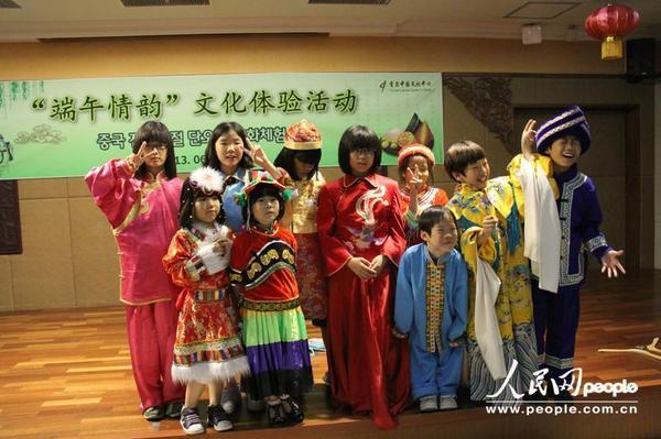 韩国小朋友试穿中国传统服装。摄影:人民网记者 马菲 人民网首尔6月12日电 (记者马菲)12日下午,首尔中国文化中心洋溢着浓浓的端午节气息。为庆祝中国端午佳节的来临,首尔中国文化中心精心组织了端午情韵文化体验活动,邀请韩国孤儿院的小朋友前来体验中国端午文化,共庆中国传统佳节。 为了让韩国小朋友更好地了解中国端午节文化,首尔中国文化中心特意准备了有关中国端午节来历和习俗的动画片。看过动画片之后,小朋友们开始跟着老师学习包粽子。看着绿油油的粽叶和丰富的馅料在老师的手中不一会儿就变成了小巧玲珑的粽子,小朋友