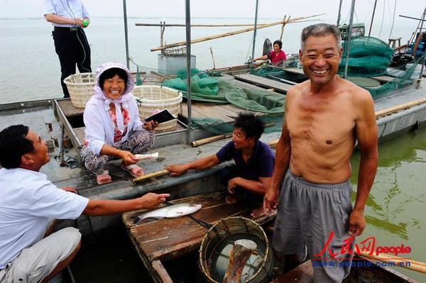 渔民闵祥营将打来的鱼卖给湖上收鱼的女老板。