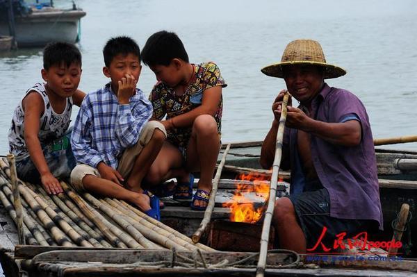 渔民胡明亮，把弯曲的竹竿烤直，然后用这些竹竿来下网养鱼。